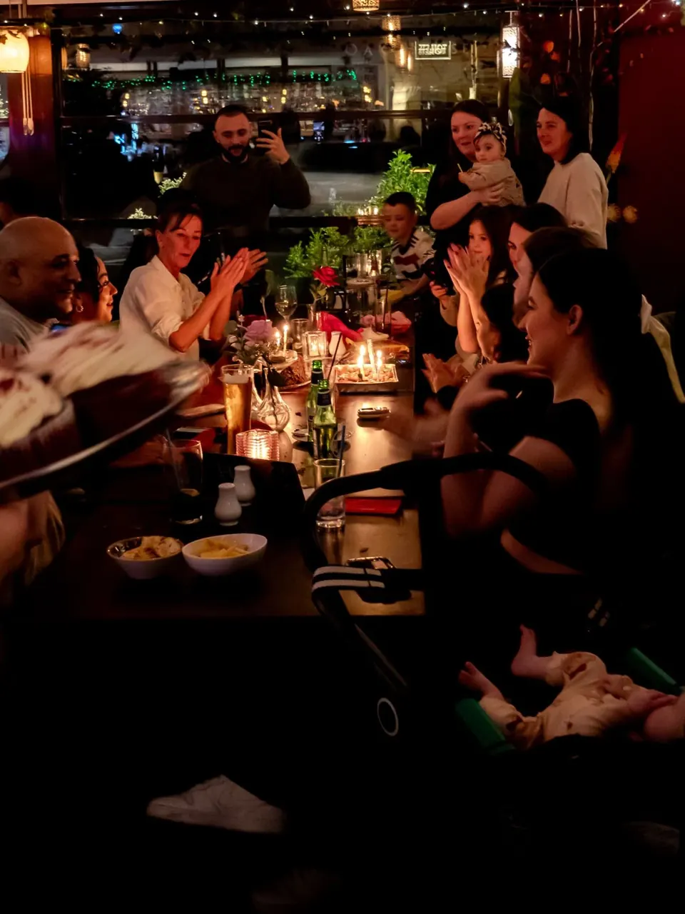 A birthday party at a long table at Istanbul Grill, with candles on the cake