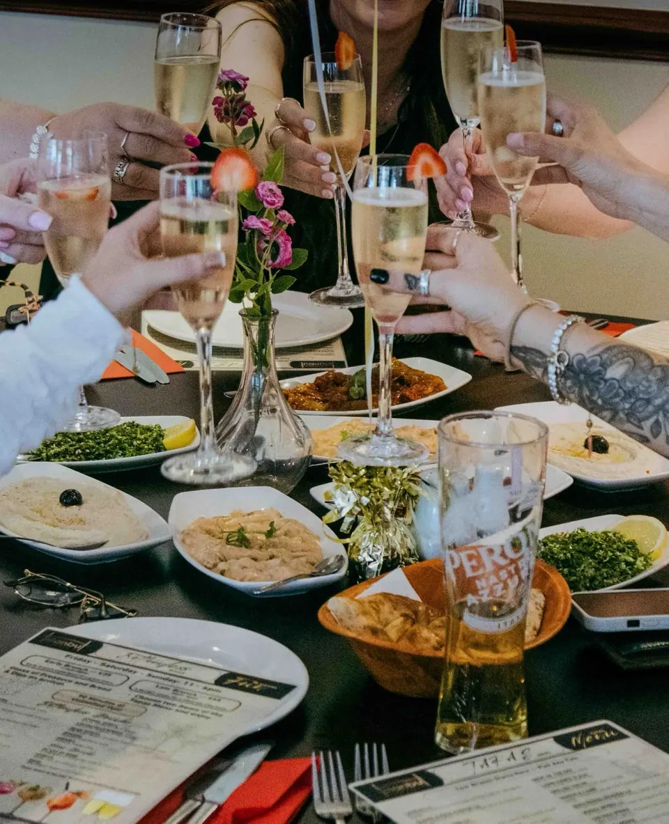 Friends raising glasses of prosecco over hummus, tabbouleh and meze at Istanbul Grill