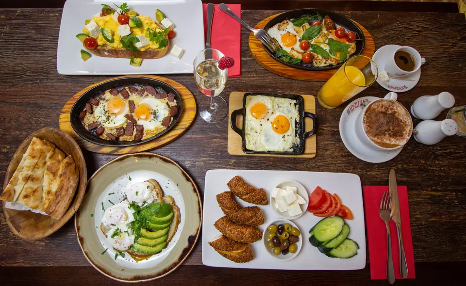 A brunch table with eggs, sucuk, avocado toast, simit and orange juice