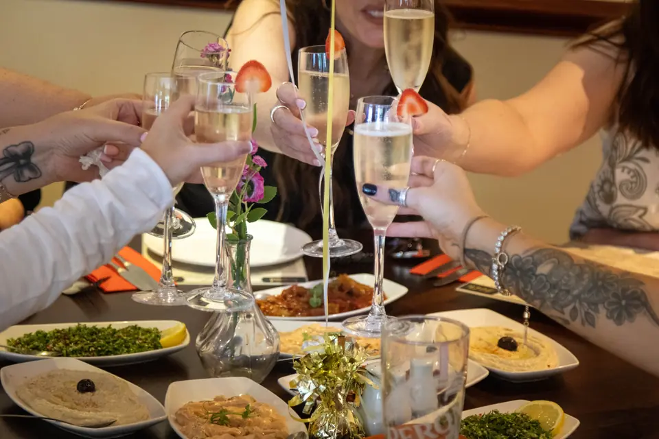 A group raising glasses of prosecco at a table of meze