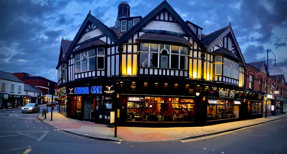 Istanbul Grill at dusk: the black-and-white corner building on Gatley Road, lit from inside