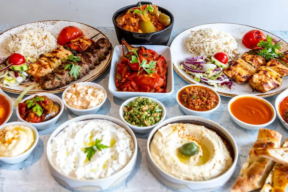 A table of Turkish meze: hummus, cacik, ezme, kebabs and bread