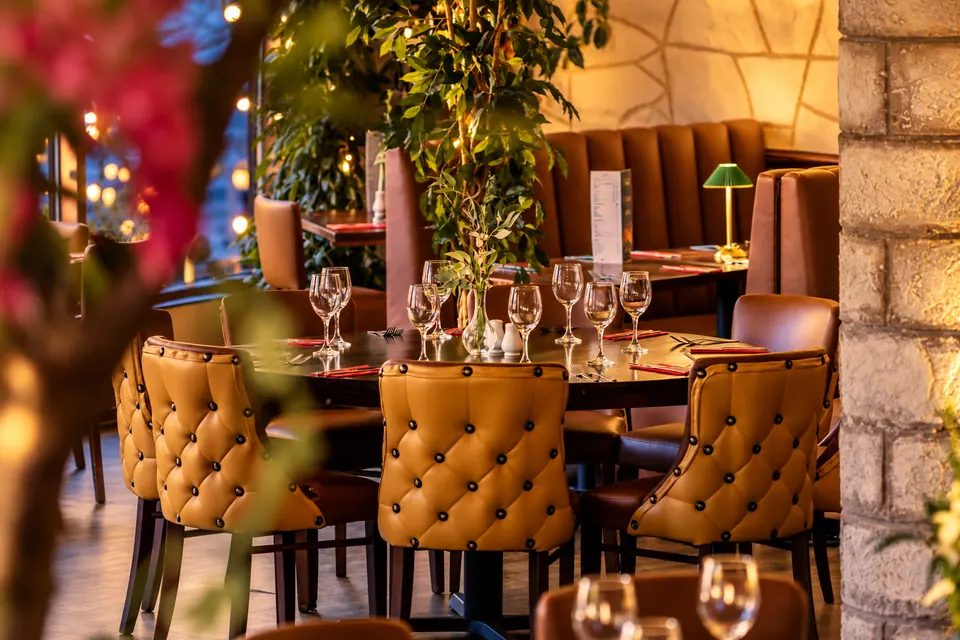Tufted mustard banquettes and tables laid for a party