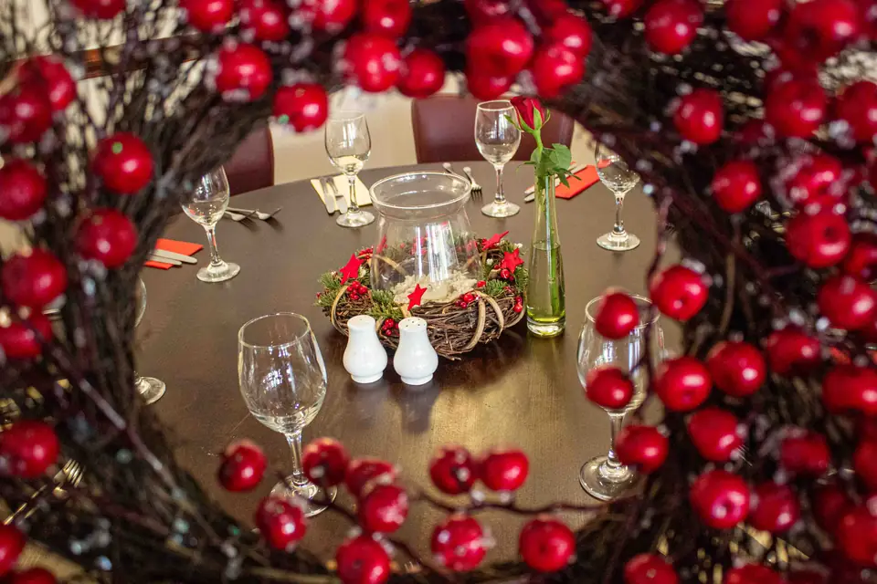 A table set for Christmas, seen through a wreath of red berries